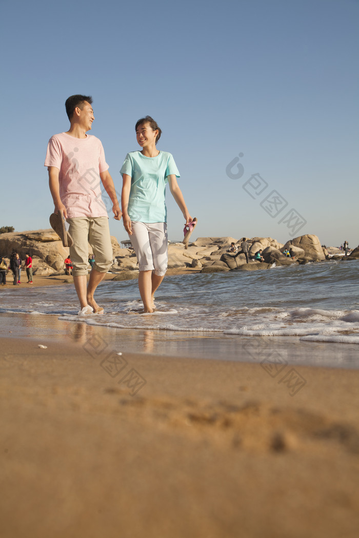 海边光脚散步的男女