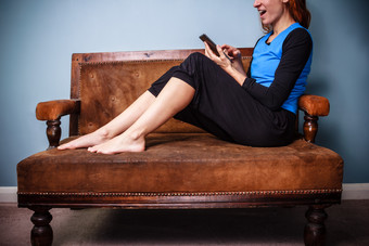 脱鞋坐沙发上玩手机的女人