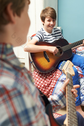 男孩开心<strong>坐在床上</strong>弹吉他