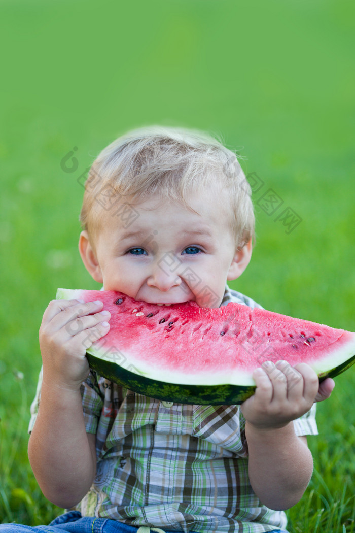 坐草地上吃西瓜的小男孩