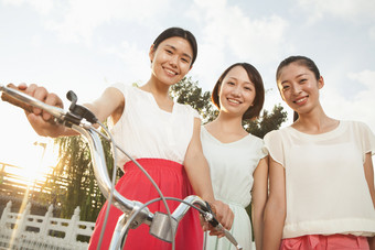 三个女人朋友闺蜜骑着单车微笑户外摄影图片