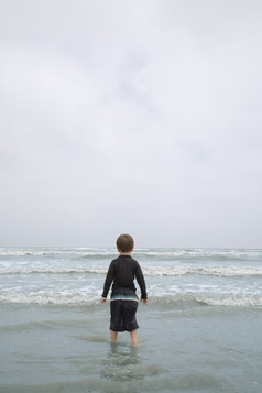 深色调大海边的儿童摄影图