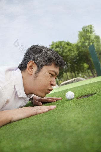 趴在草坪上吹高尔夫球