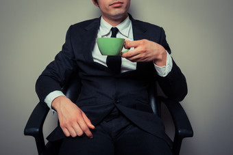 坐着喝咖啡的西装男摄影图
