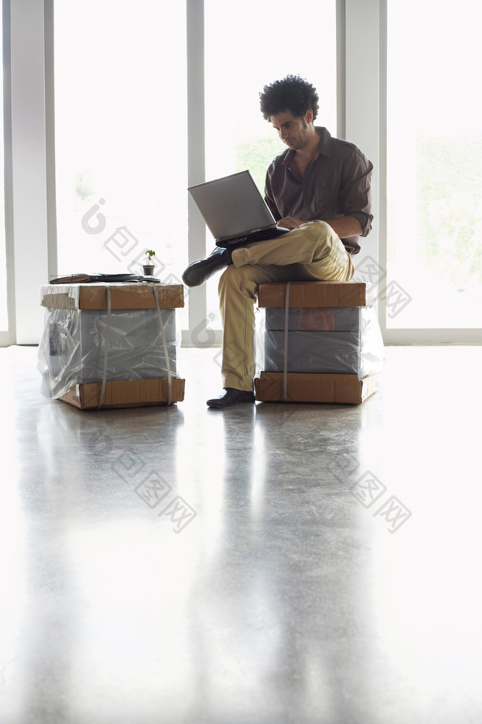 坐箱子上电脑上网的男人