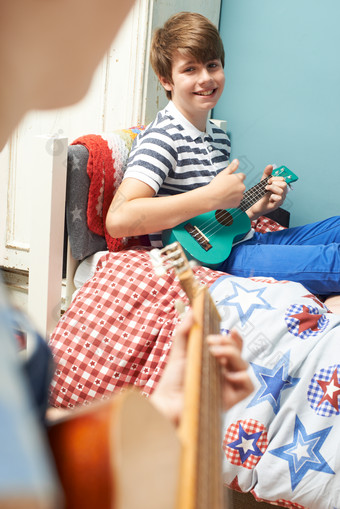 男孩坐在床上弹吉他