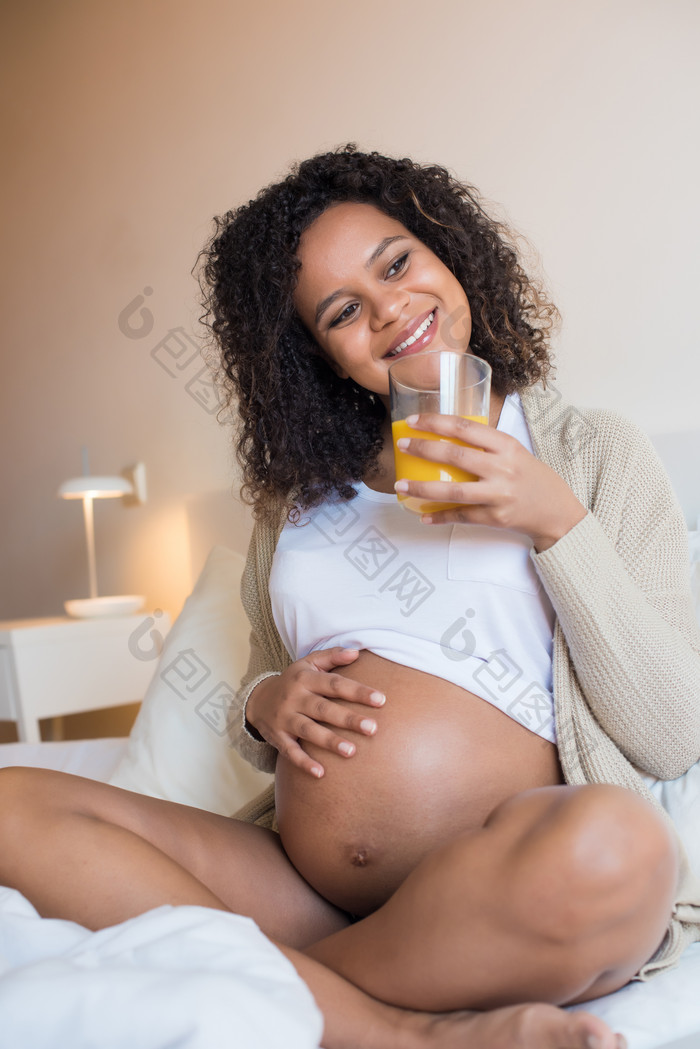黑人孕妇开心摸着肚子喝橙汁