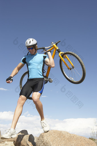 男人扛着自行车踩在石头上