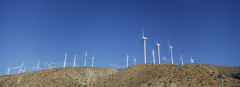 蓝色调山上的风力发电摄影图
