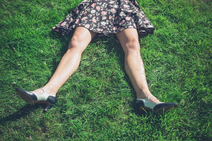 暗色调草地上躺着的女人的腿摄影图