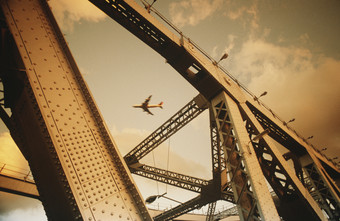 暗色调大桥上的飞机摄影图