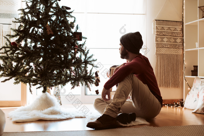 圣诞树旁坐着的男士