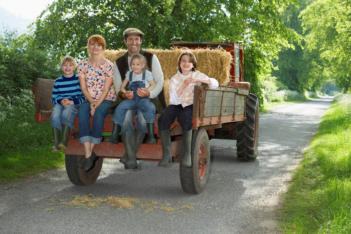 暗色调坐拖拉机的家人摄影图
