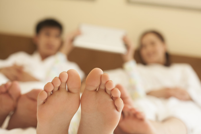 爸爸妈妈小孩一家人家庭躺床上玩平板摄影图