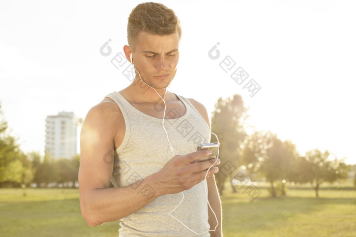 草地上戴耳机听音乐的男人