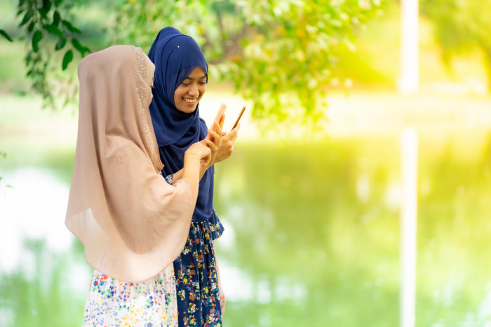 湖边看手机的穆斯林美女