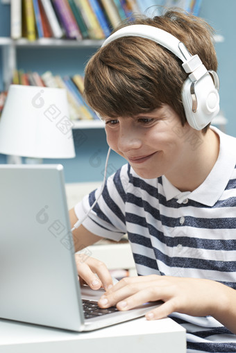 男孩戴着耳机看笔记本电脑