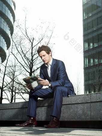 商务男士坐在户外看报纸