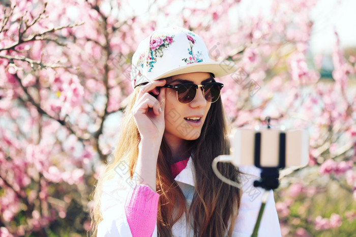 樱花树前手机拍照的女人