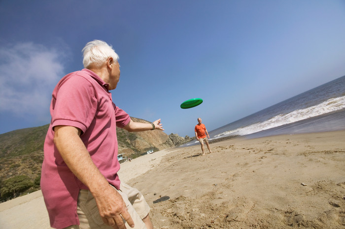 沙滩玩飞盘的老人