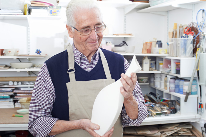 简约风格学做陶器的老人摄影图