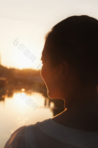 夕阳美女女人背影户外旅游河边微笑摄影图片