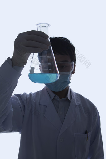 实验室做实验的年轻人男子测量杯蓝色的<strong>液体</strong>