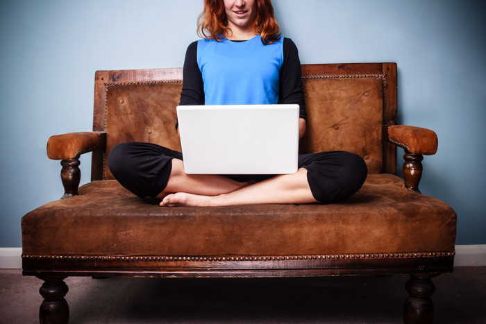 盘腿坐沙发上玩电脑的女人