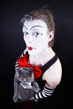 暗色抱猫的小丑男摄影图