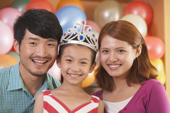 小女孩生日派对戴着皇冠微笑爸爸妈妈摄影图