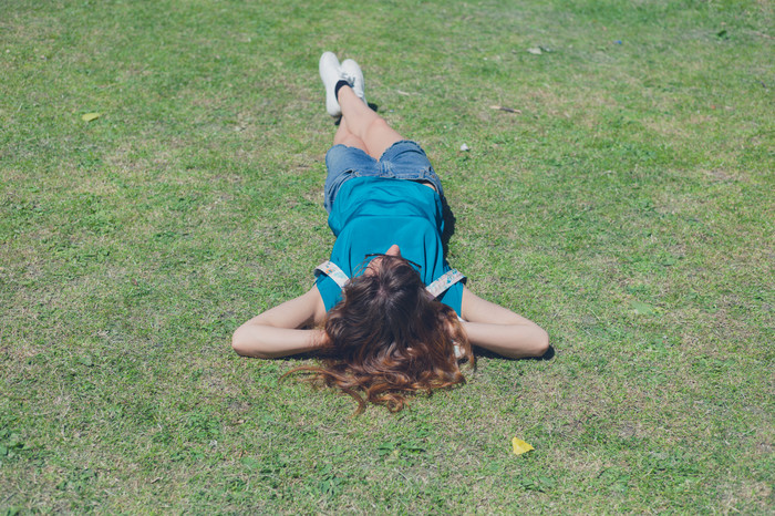 绿色调在草地上躺着的女孩摄影图