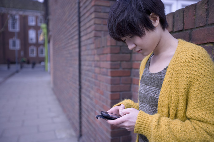 暗色调看手机的女孩摄影图