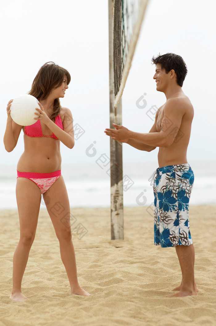 深色调打沙滩排球的情侣摄影图