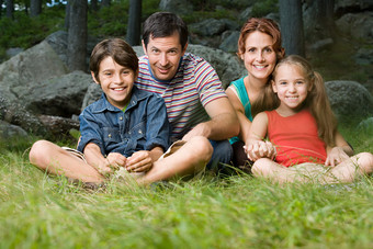 暗色调坐在草地上的家人摄影图