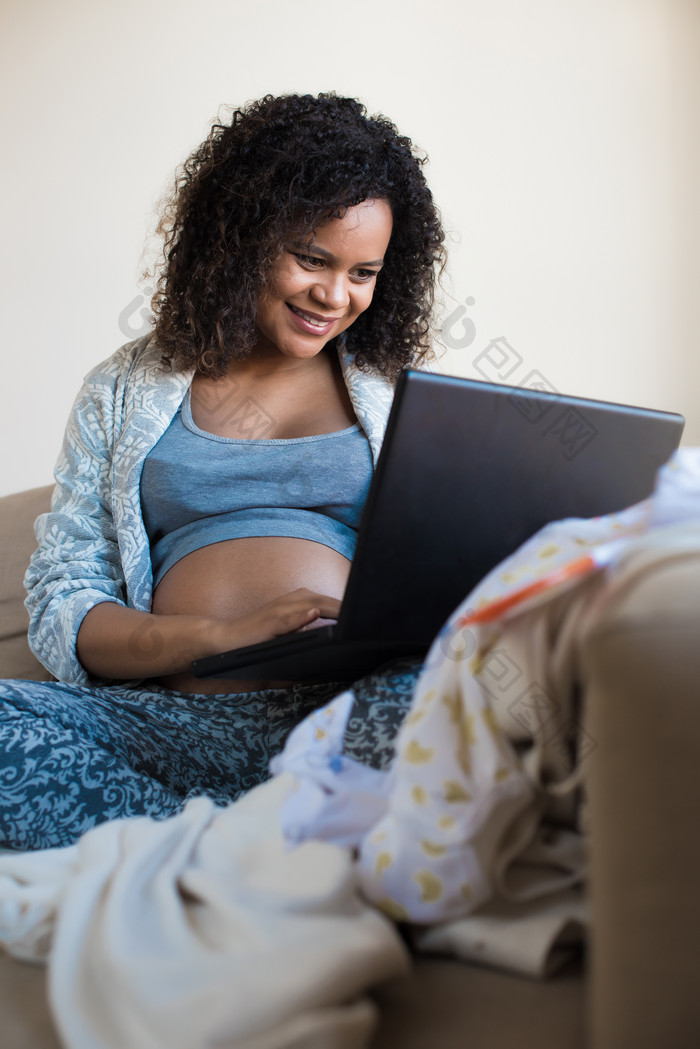 黑人孕妇坐在沙发上看笔记本电脑