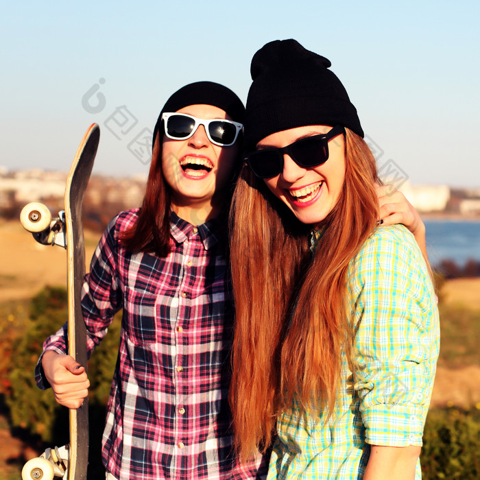 两个女孩抱着滑板大笑