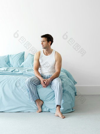 简约床上坐着的男人摄影图