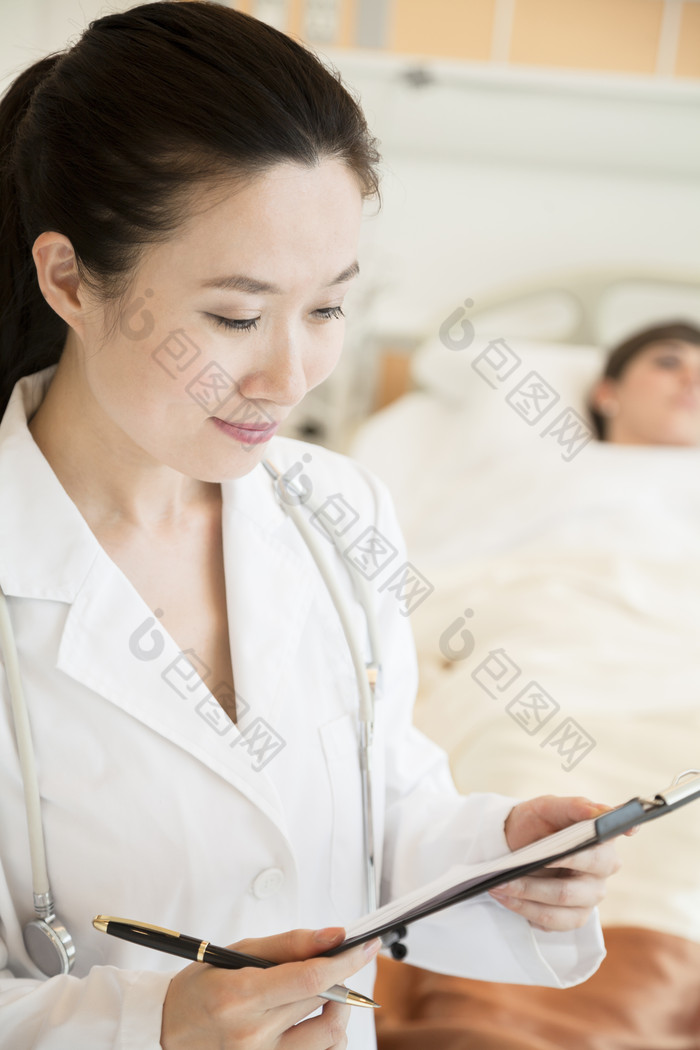 医生站在病床前查看病人病历