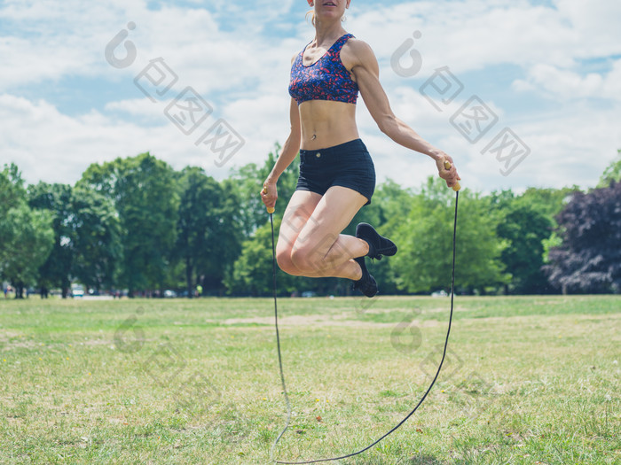 绿色调草地上跳绳的女人摄影图