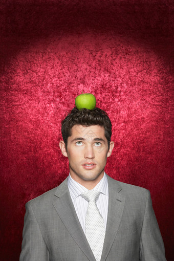 商务男士抬眼看着头上的青苹果