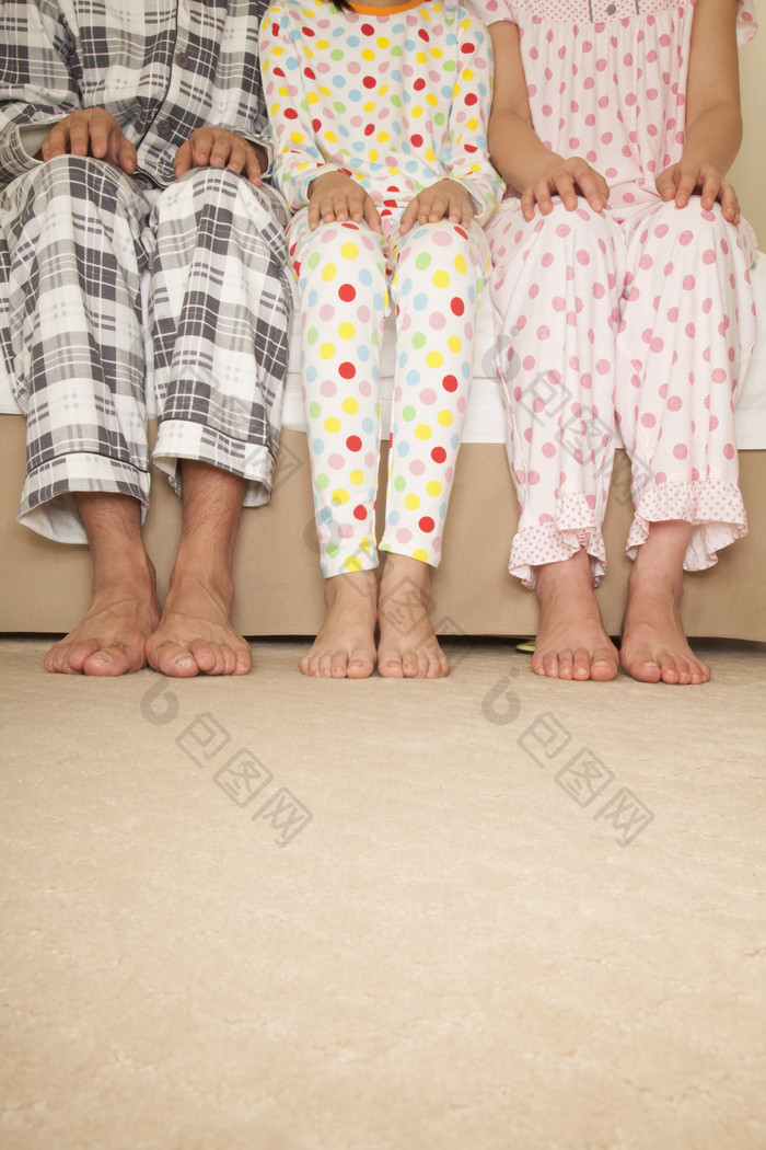 一家三口穿着睡衣坐着爸爸妈妈女儿坐在沙发