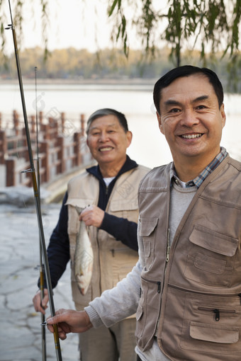 两个男人户外钓鱼河边码头微笑新鲜的鱼竿