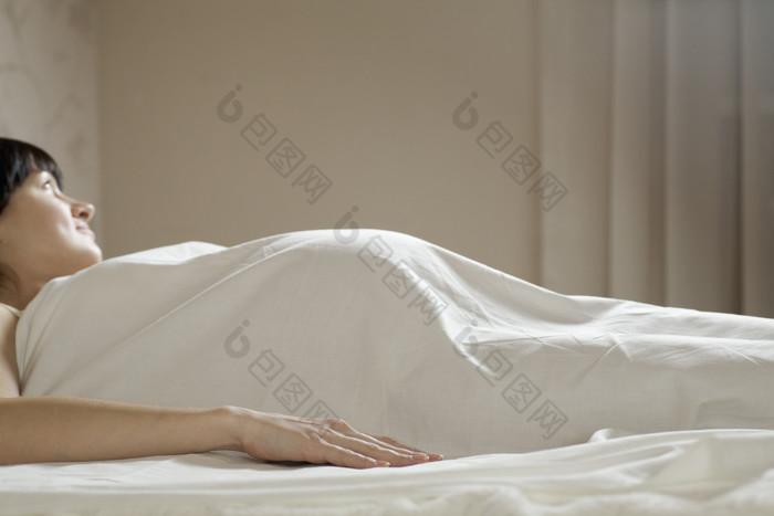 深色调睡觉的孕妇摄影图