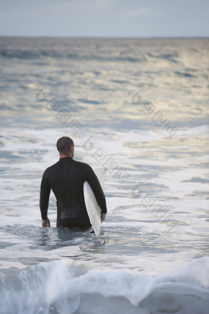 暗色调海中冲浪的男人摄影图