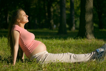 深色调草地上的孕妇摄影图