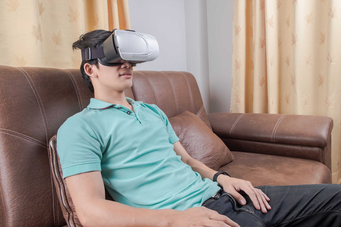 坐沙发上体验VR眼镜的男人