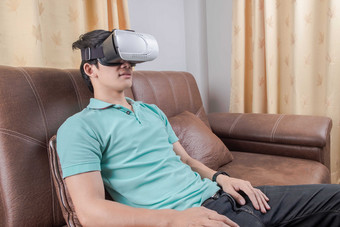 坐沙发上体验<strong>VR</strong>眼镜的男人