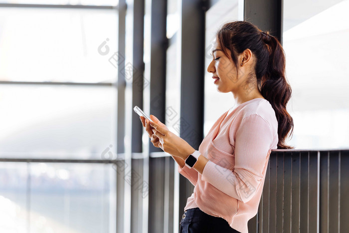 靠着栏杆看手机的女人