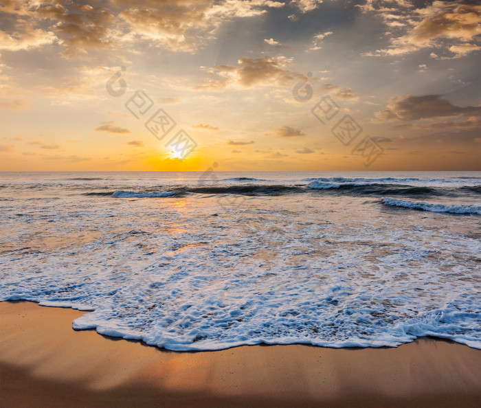 海边落日下的沙滩海浪摄影图
