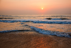 落日下翻滚的海浪摄影图
